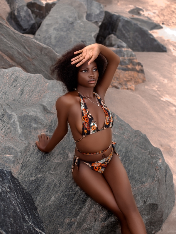 Woman In A Patterned Bikini Posing Against Large Coastal Rocks.